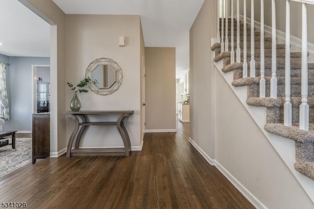 entryway with stairs, baseboards, and wood finished floors