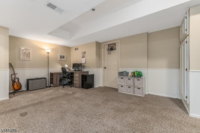 carpeted home office with a wainscoted wall, a raised ceiling, and visible vents