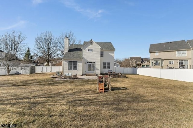 rear view of house featuring entry steps, a lawn, a chimney, and a fenced backyard