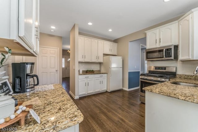 kitchen featuring appliances with stainless steel finishes, dark wood finished floors, white cabinetry, and light stone countertops