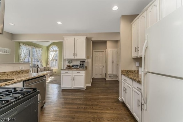 kitchen with dark wood-type flooring, stone countertops, freestanding refrigerator, and white cabinets