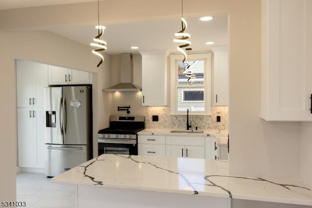 kitchen with stainless steel appliances, tasteful backsplash, white cabinets, a sink, and wall chimney range hood