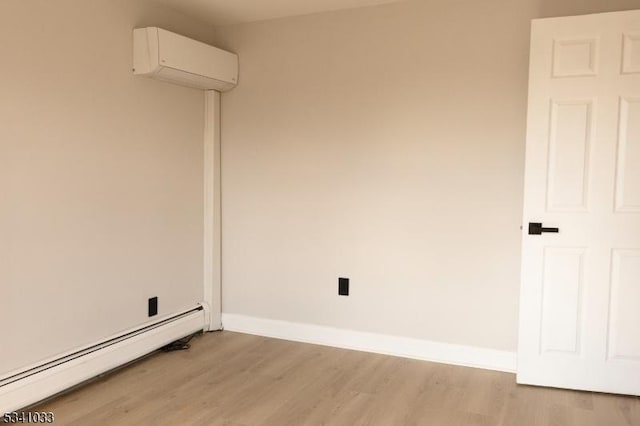 unfurnished room with baseboards, a baseboard heating unit, light wood-style flooring, and an AC wall unit