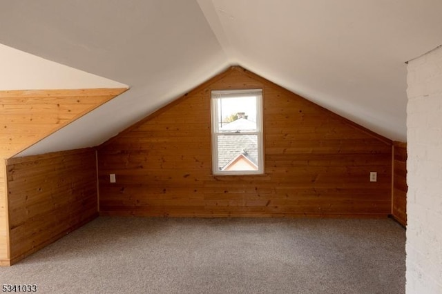 additional living space featuring wood walls, vaulted ceiling, and light colored carpet