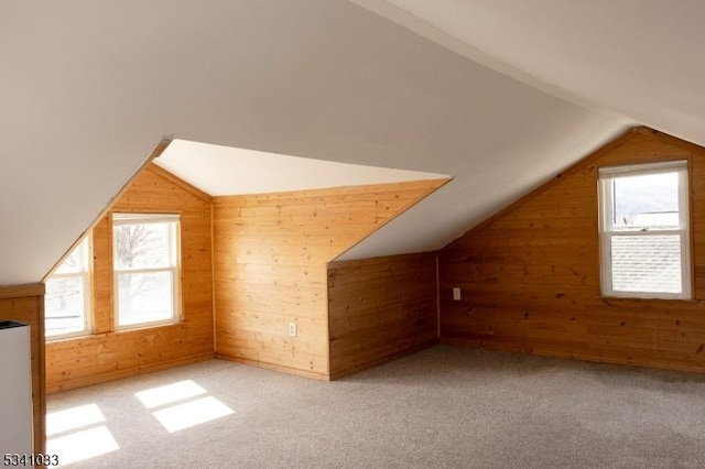 additional living space with carpet, vaulted ceiling, plenty of natural light, and wooden walls