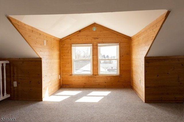 additional living space featuring lofted ceiling, carpet floors, and wood walls