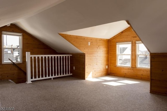 bonus room with a healthy amount of sunlight, wooden walls, and lofted ceiling