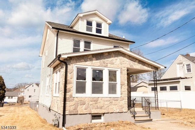 view of front of house with stone siding and fence