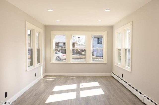 unfurnished room featuring a baseboard radiator, recessed lighting, baseboards, and wood finished floors