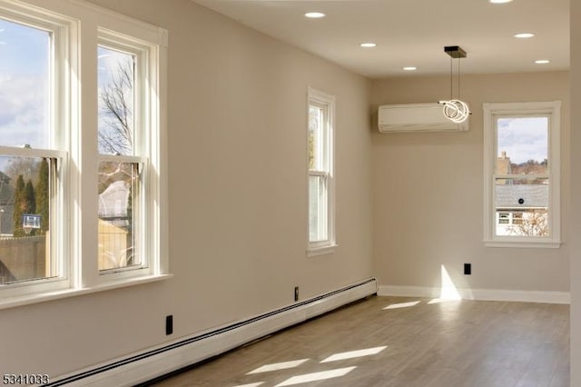 spare room featuring a baseboard radiator, recessed lighting, an AC wall unit, wood finished floors, and baseboards