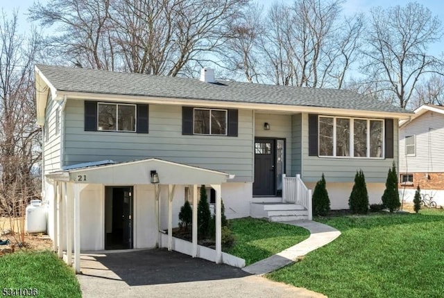 view of front of house with a front lawn, driveway, a chimney, and roof with shingles