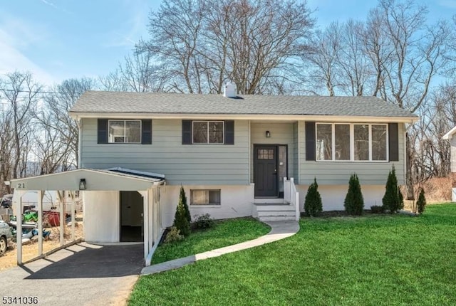 raised ranch featuring a front lawn, driveway, and a shingled roof