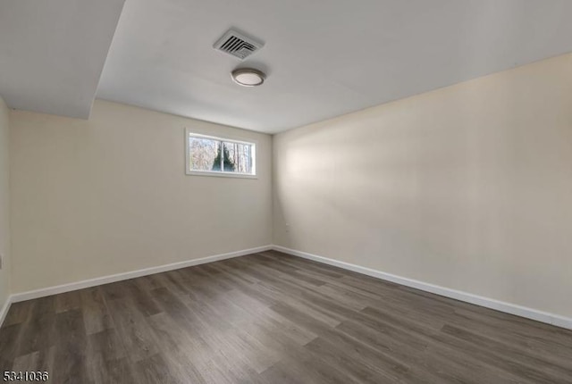 empty room featuring visible vents, baseboards, and dark wood finished floors