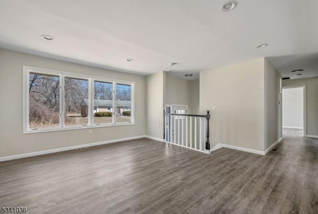 spare room featuring recessed lighting, baseboards, and dark wood-style floors