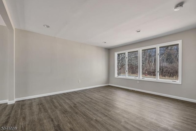 spare room with baseboards and dark wood-type flooring