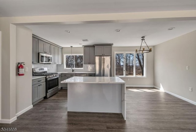 kitchen with pendant lighting, tasteful backsplash, appliances with stainless steel finishes, and gray cabinetry