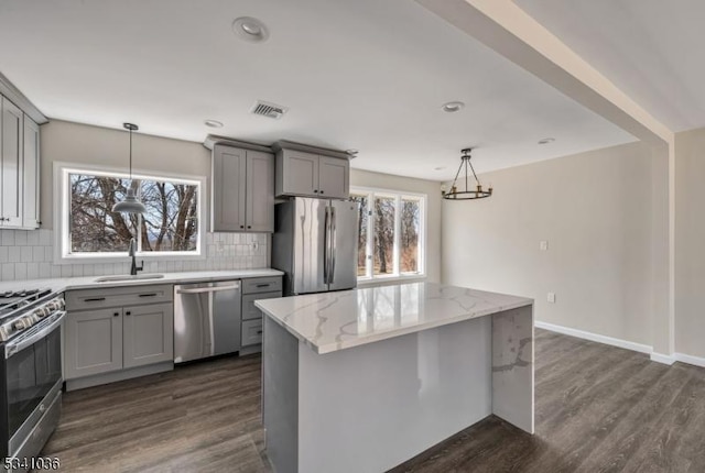 kitchen featuring visible vents, gray cabinets, a sink, stainless steel appliances, and tasteful backsplash