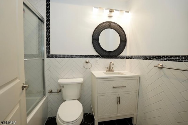 full bath featuring enclosed tub / shower combo, tile patterned flooring, toilet, vanity, and tile walls