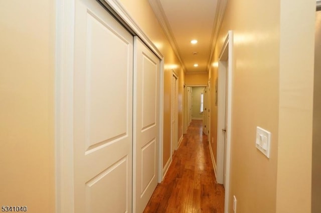 hallway featuring baseboards, ornamental molding, wood finished floors, and recessed lighting