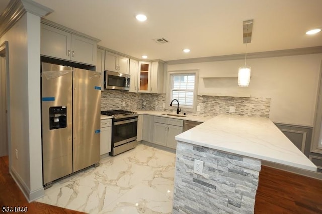 kitchen with marble finish floor, decorative backsplash, appliances with stainless steel finishes, a sink, and a peninsula