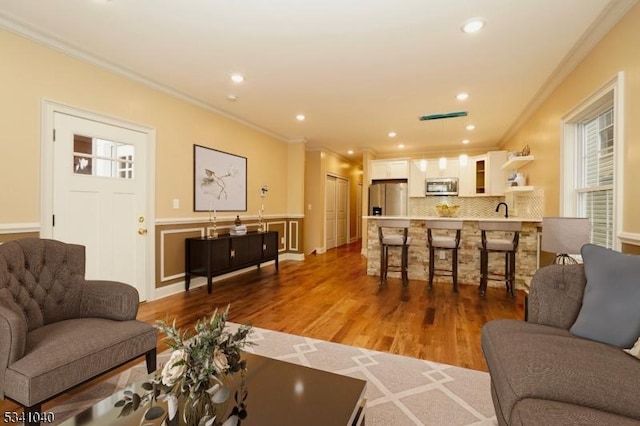 living room with ornamental molding, recessed lighting, and light wood-style floors