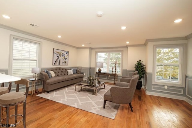 living room with light wood-type flooring, a wainscoted wall, plenty of natural light, and visible vents