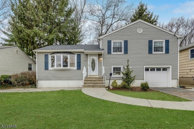 tri-level home with an attached garage, concrete driveway, a front yard, and roof with shingles