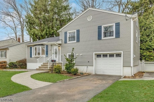 tri-level home featuring aphalt driveway, an attached garage, and fence