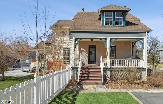 view of front of property with a fenced front yard, covered porch, and a shingled roof