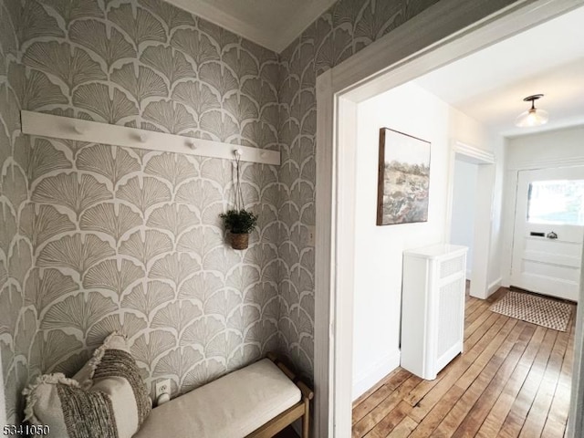 interior space featuring baseboards, wallpapered walls, and light wood-style floors