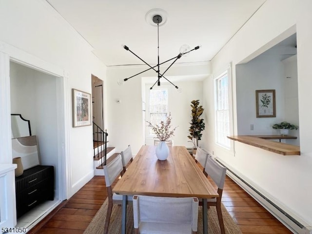 dining space with crown molding, baseboards, a chandelier, baseboard heating, and hardwood / wood-style flooring