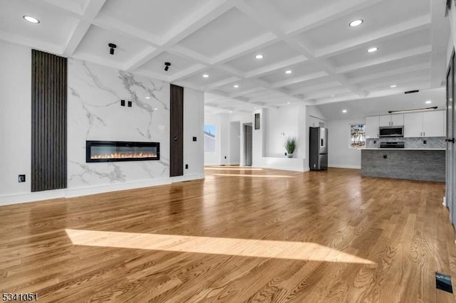 unfurnished living room featuring a premium fireplace, coffered ceiling, wood finished floors, and recessed lighting