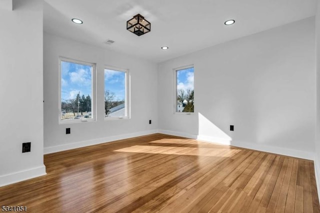 unfurnished room featuring baseboards, wood finished floors, and recessed lighting