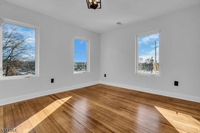 interior space with wood-type flooring, visible vents, and baseboards