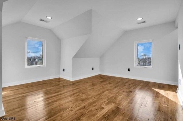 additional living space with lofted ceiling, wood finished floors, visible vents, and baseboards