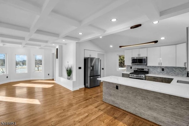 kitchen featuring stainless steel appliances, beam ceiling, white cabinetry, and a peninsula