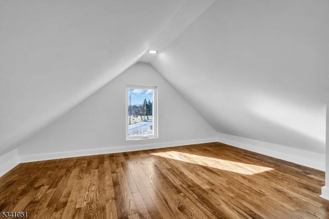 additional living space with wood-type flooring, vaulted ceiling, and baseboards