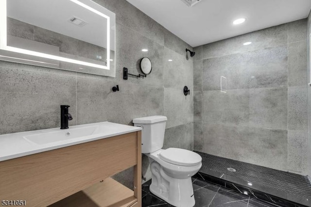 full bath with toilet, visible vents, vanity, tile walls, and tiled shower