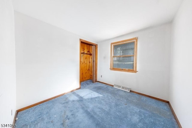 carpeted spare room featuring visible vents and baseboards