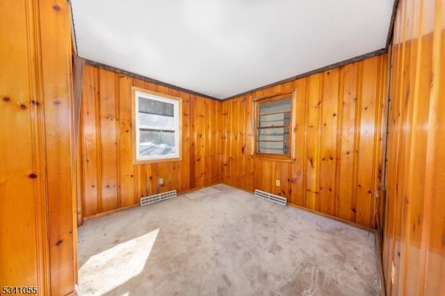 unfurnished room with carpet floors, visible vents, and wooden walls