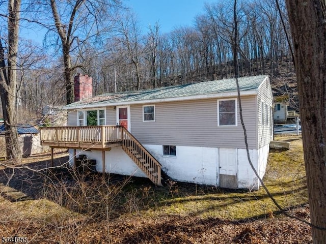 back of property with stairs, a deck, and a chimney