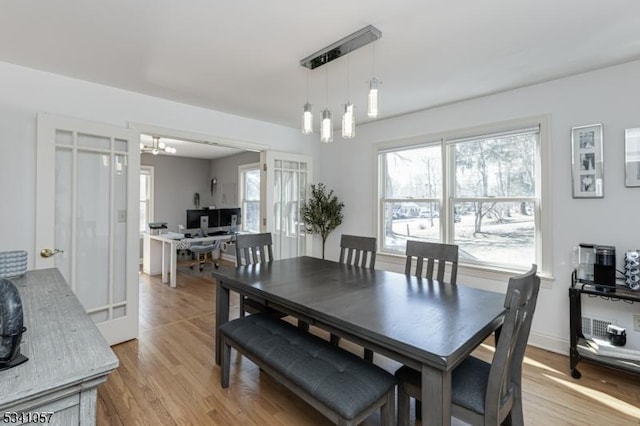 dining room with light wood-style flooring and a notable chandelier