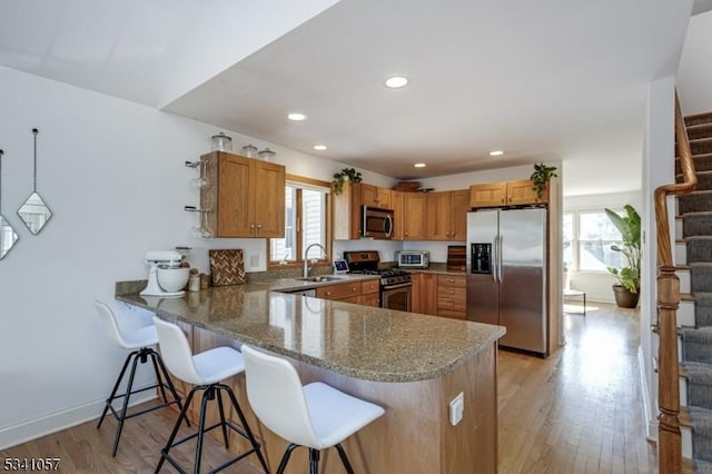 kitchen with a peninsula, appliances with stainless steel finishes, a breakfast bar area, and plenty of natural light