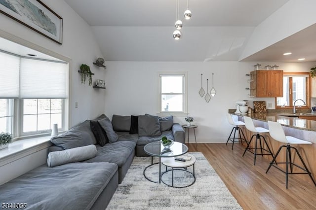 living area with lofted ceiling, plenty of natural light, and light wood finished floors