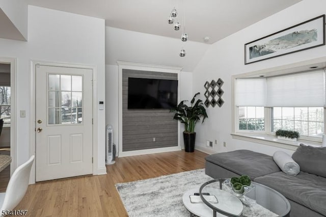 living room with a healthy amount of sunlight, light wood-type flooring, baseboards, and vaulted ceiling