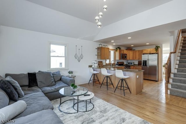 living room with a healthy amount of sunlight, light wood-style flooring, and stairway