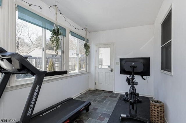 exercise area featuring baseboards and stone tile floors