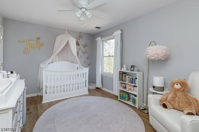 bedroom featuring visible vents, wood finished floors, a ceiling fan, and baseboards