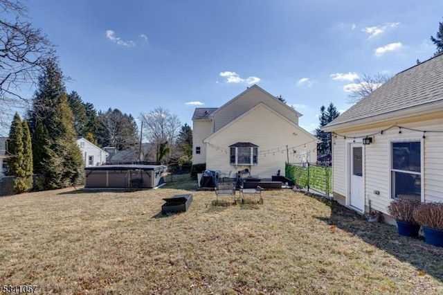 back of property featuring a shingled roof, a yard, a swimming pool, and fence