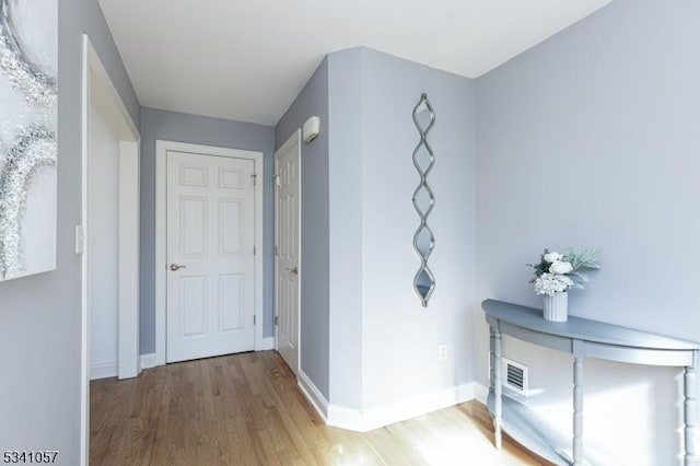 hallway with visible vents, baseboards, and wood finished floors